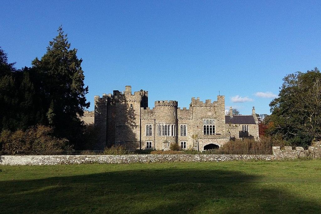 Haltwhistle | A medieval stone castle with turrets, set in the countryside surrounded by trees.