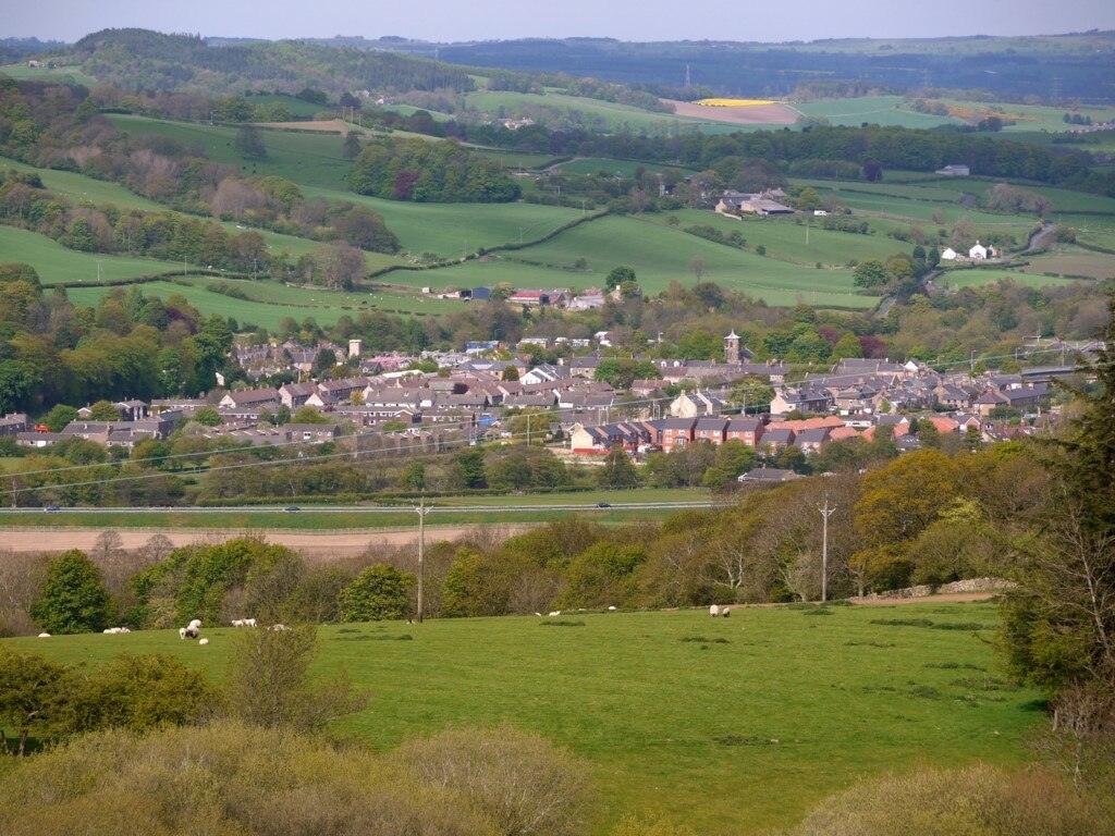 Haydon Bridge | Aerial view of a small village surrounded by green fields and rolling hills.