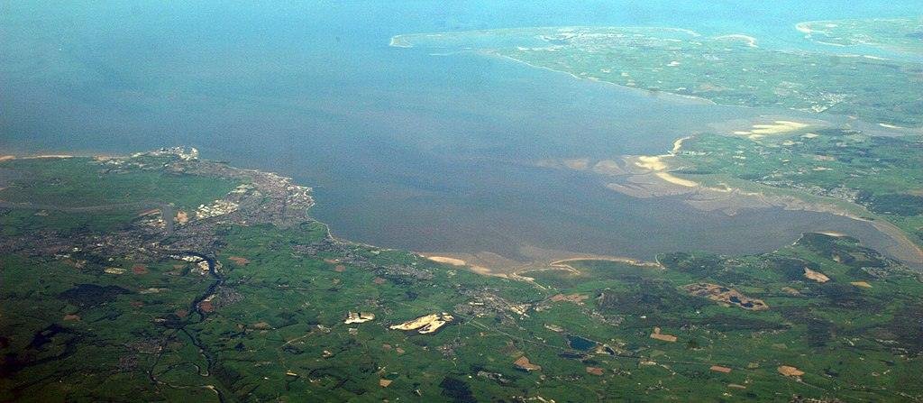 Aerial view of Morecambe Bay in Lancashire, England, showing surrounding land, towns, and coastal areas.