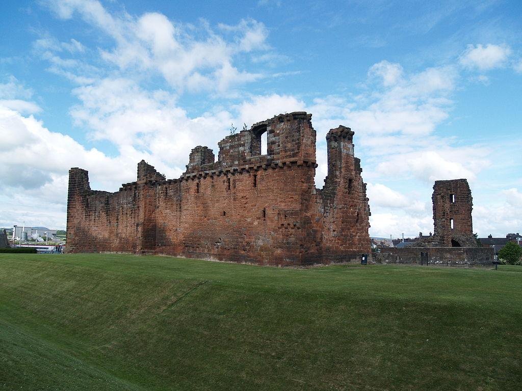 Penrith Castle | Ruins of a red sandstone castle with grassy surroundings under a partly cloudy sky.