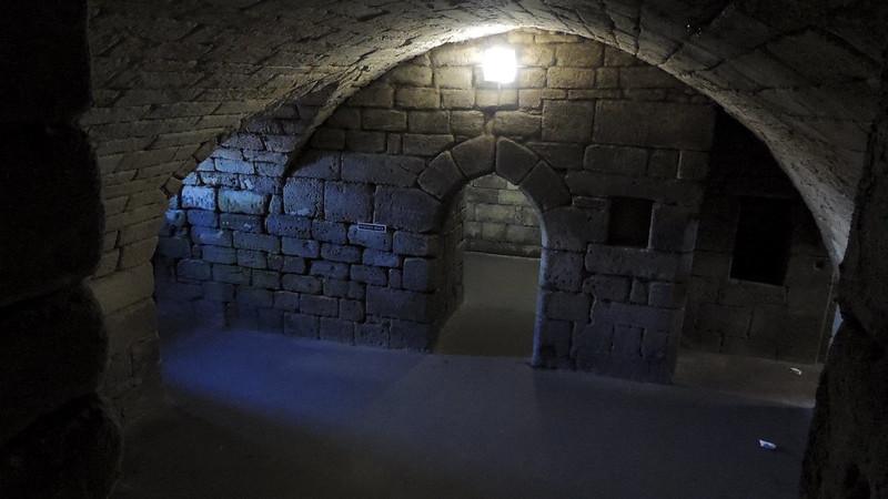 Stone archways and walls inside a dimly lit underground chamber.