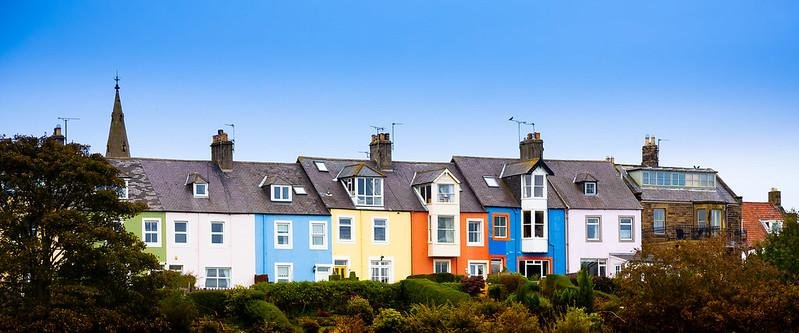 Alnmouth | Row of colourful terraced houses with a church spire in the background.