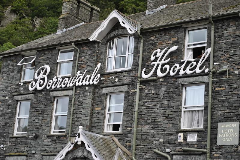 Exterior of Borrowdale Hotel with stone walls and white cursive signage.