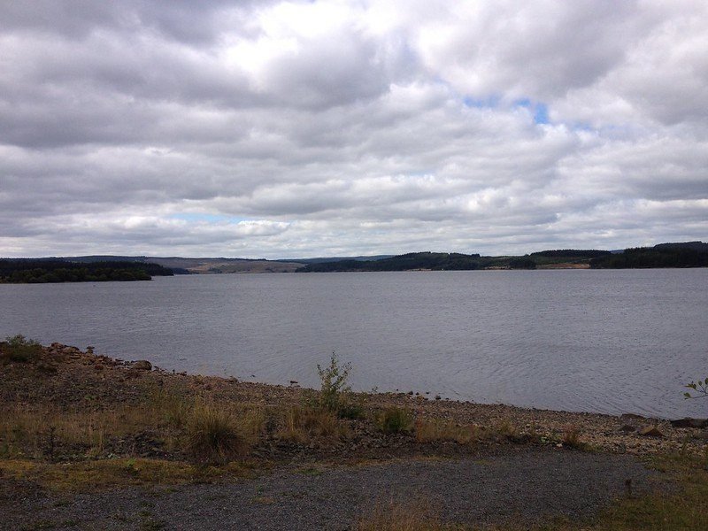 A lake with a rocky shoreline under a cloudy sky.