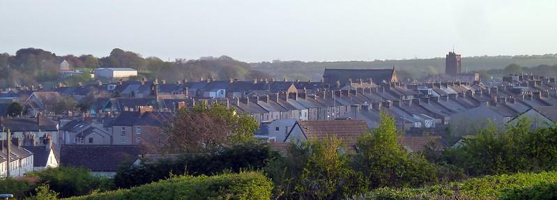 Dalton-in-Furness, Cumbria, A Row of terraced houses with a church tower in the background and greenery in the foreground.