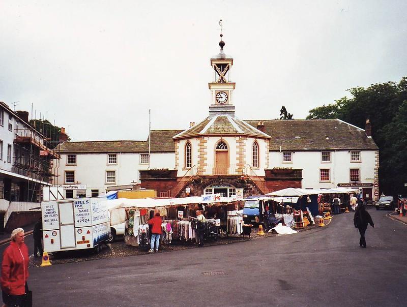 Brampton, Cumbria | Outdoor market stalls in front of a historic building with a clock tower.