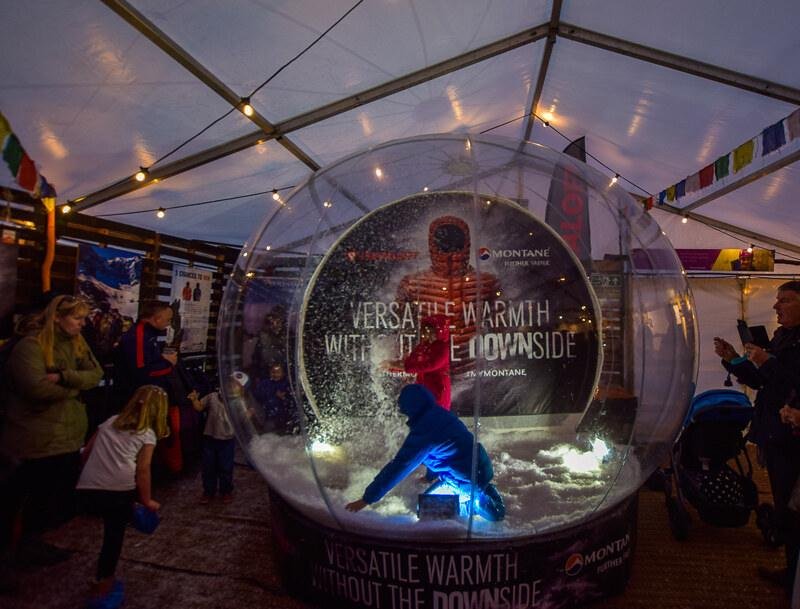 Kendal Mountain Festival, Cumbria | Children playing inside an illuminated snow globe at an indoor event with spectators watching.