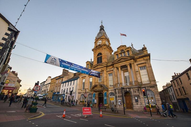 Kendal Mountain Festival, Cumbria | Historic town hall building with clock tower, banners for the Kendal Mountain Festival, and street closed to traffic.