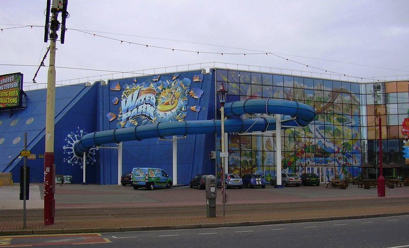 Exterior of a water park building with a large waterslide and colourful mural.