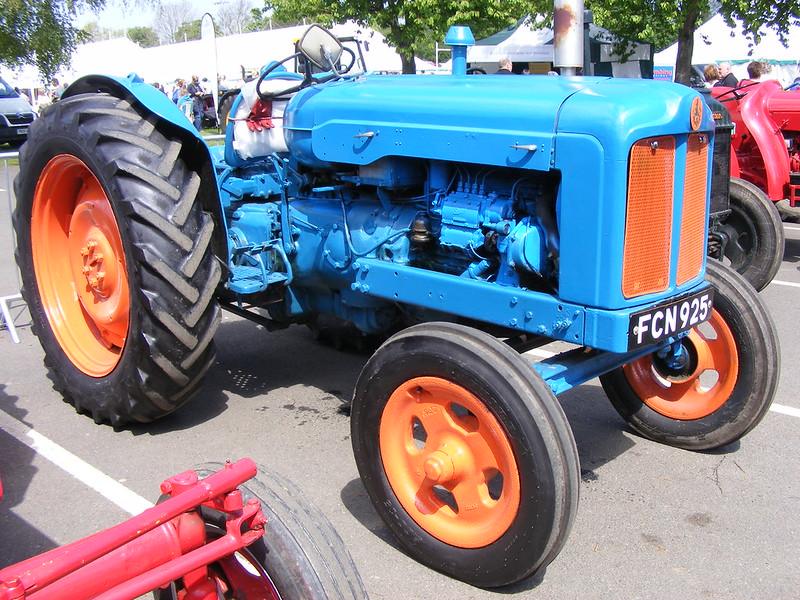 Blue vintage tractor with orange wheels on display.