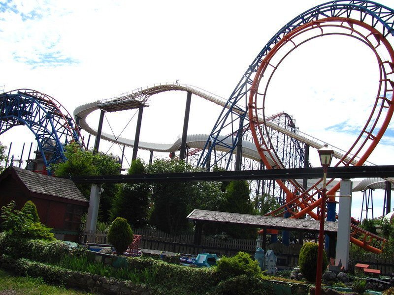 Roller coaster with multiple loops and colourful tracks in a theme park setting.