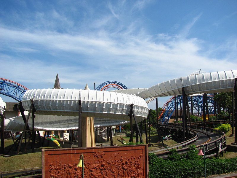 Amusement park ride with intertwined tracks and slides under a blue sky.