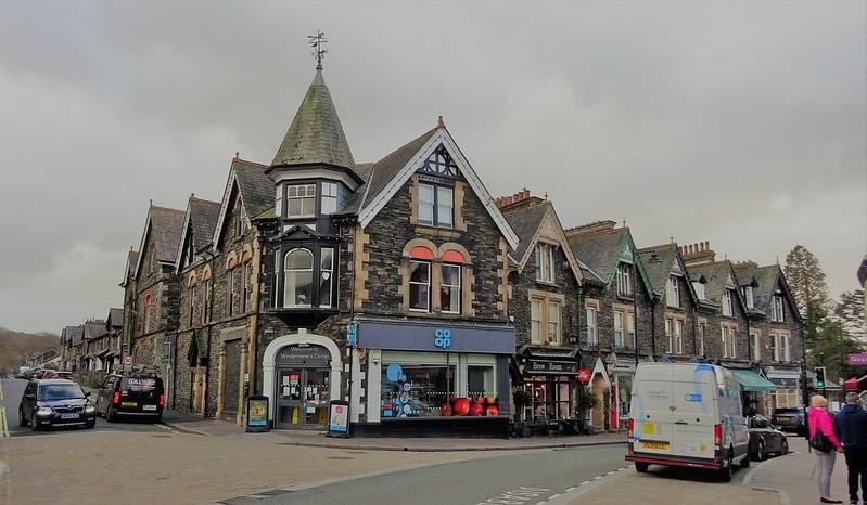 Street view of a row of Victorian-style buildings with shops, including a Co-op grocery store, a wine bar, and various other businesses.