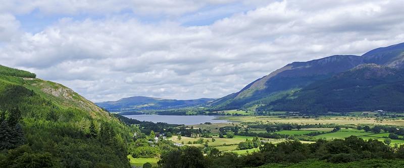 Bassenthwaite, Cumbria | Scenic rural landscape with mountains, a lake, and lush green fields under a partly cloudy sky.