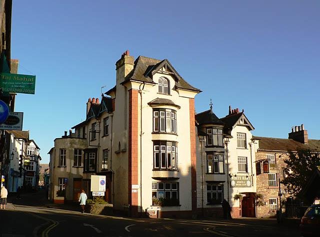 White Hart Hotel with adjacent buildings on a sunny street corner.