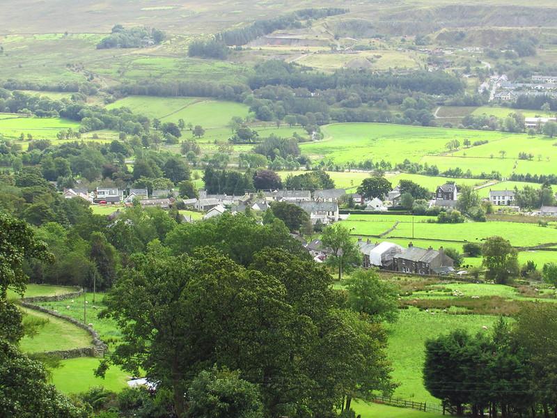 Aerial view of a small village surrounded by lush green fields and trees.