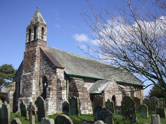 Stone church with a bell tower surrounded by a cemetery.