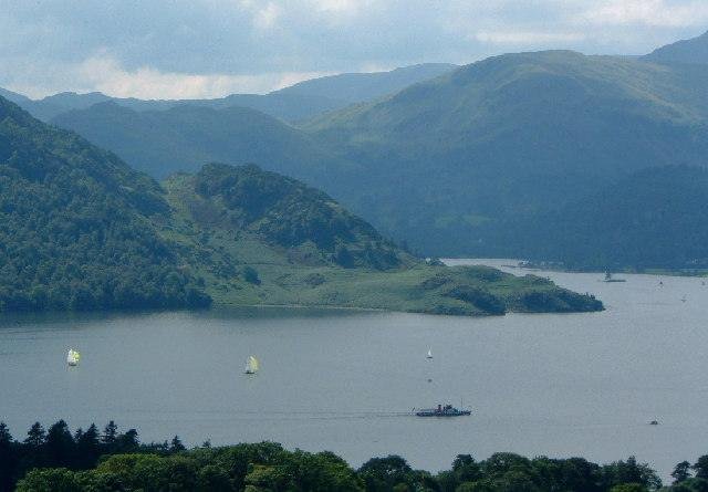 Lake surrounded by hills with boats sailing on the water.