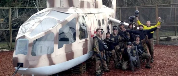 A group of people in paintball gear standing in front of a helicopter model.