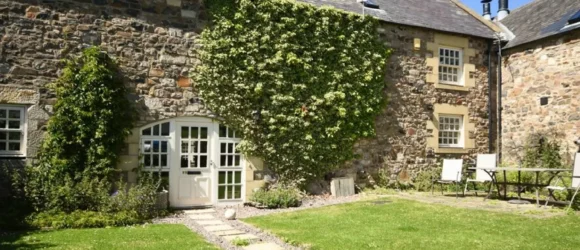 Stone cottage with a garden path and climbing greenery on the facade.