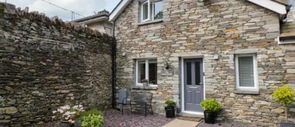 Stone cottage with a grey door and a small courtyard.